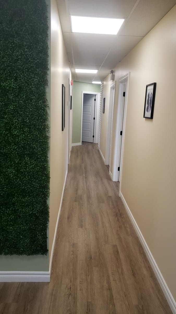 The corridor to the treatment rooms at The Wellness Zone, with the clinic's green foliage wall